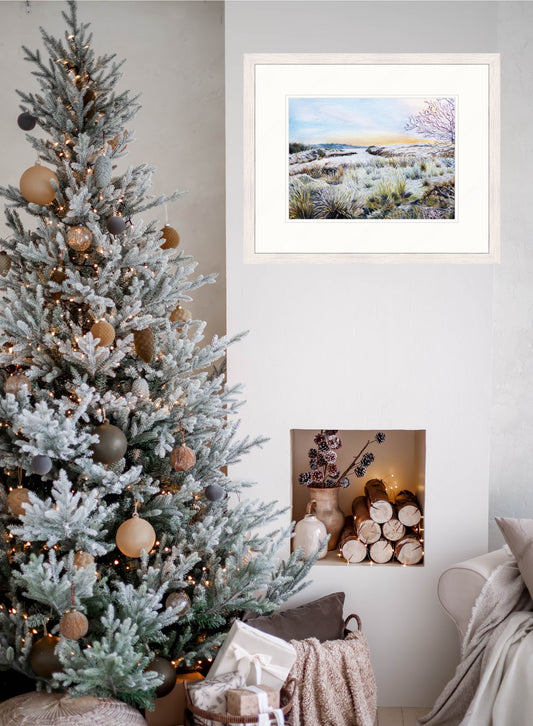 Decorated Christmas tree with ornaments next to a framed original winter painting on a wall.